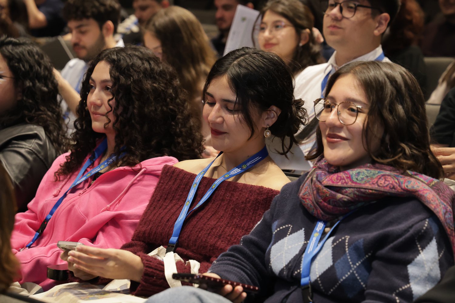 Participantes conversan en las butacas del auditorio.