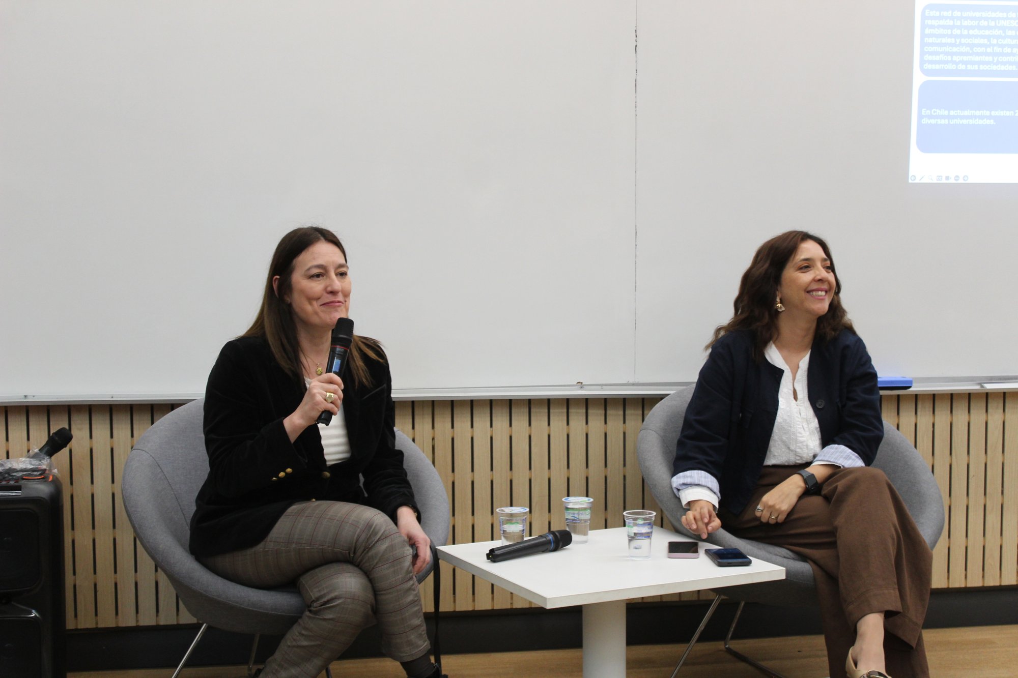 Dos expositoras conversan frente al público en una sala.