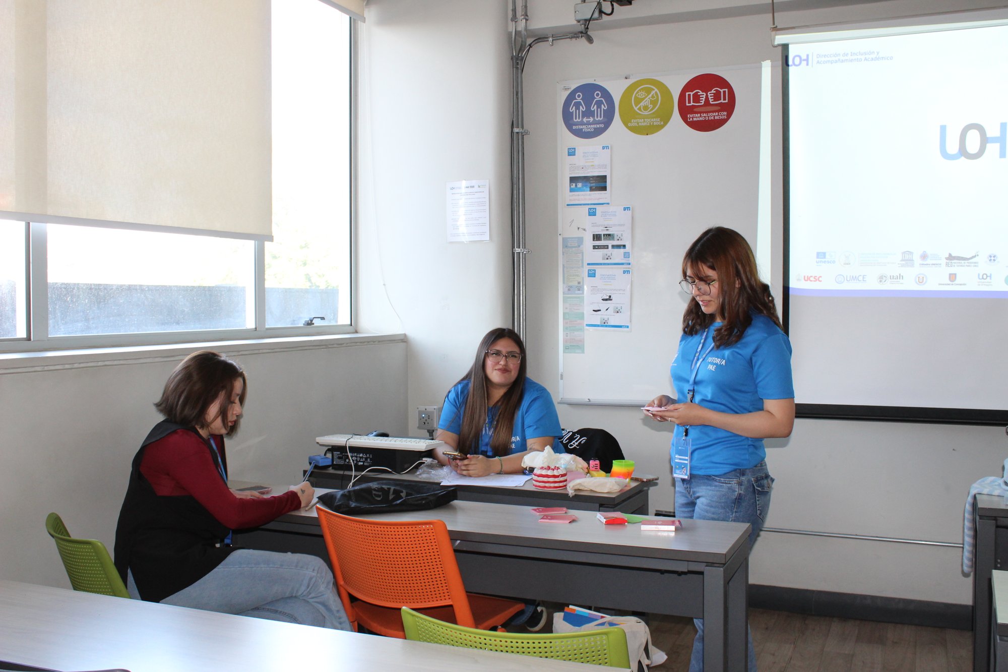 Una expositora presenta frente a un grupo en una sala.