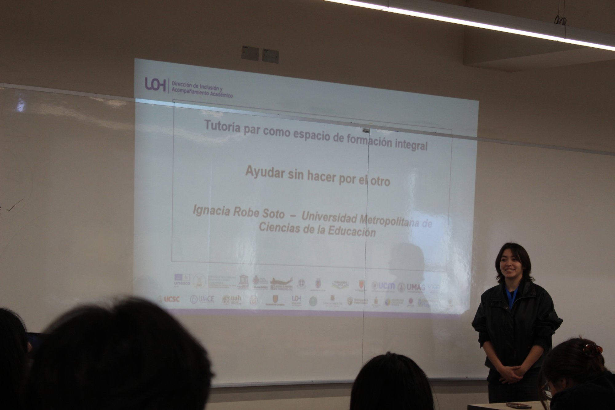 Una expositora junto a la proyección de su presentación.