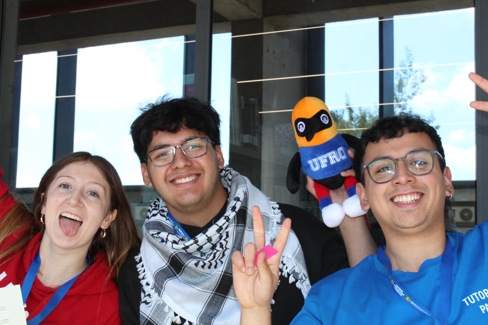 Tres participantes posan con una mascota de su delegación.