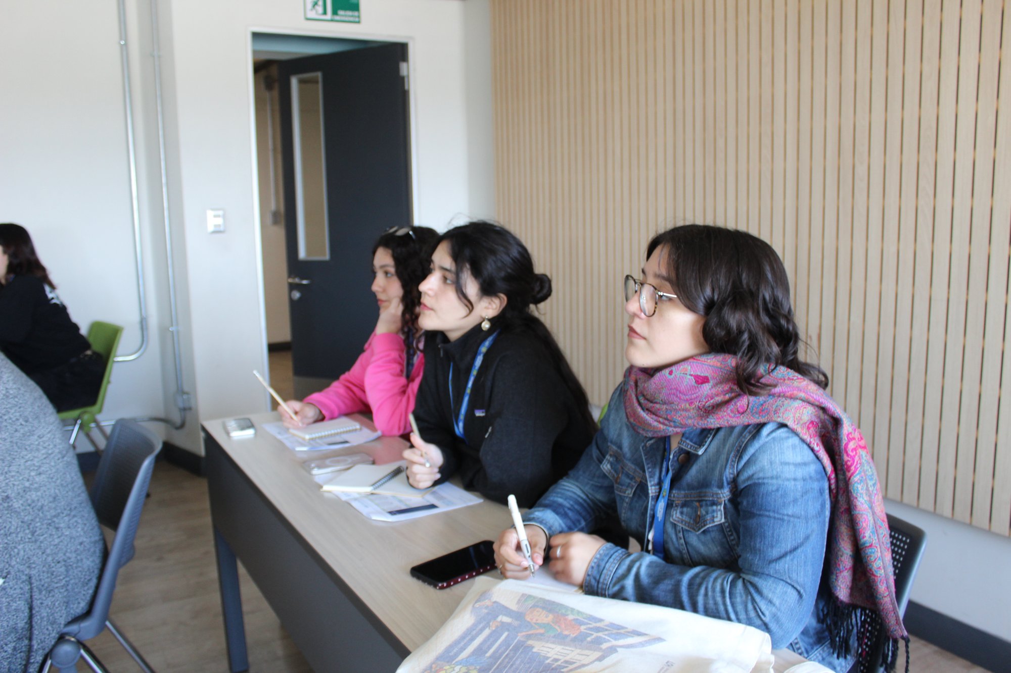 Expositoras sentadas al frente de una sala de clases.