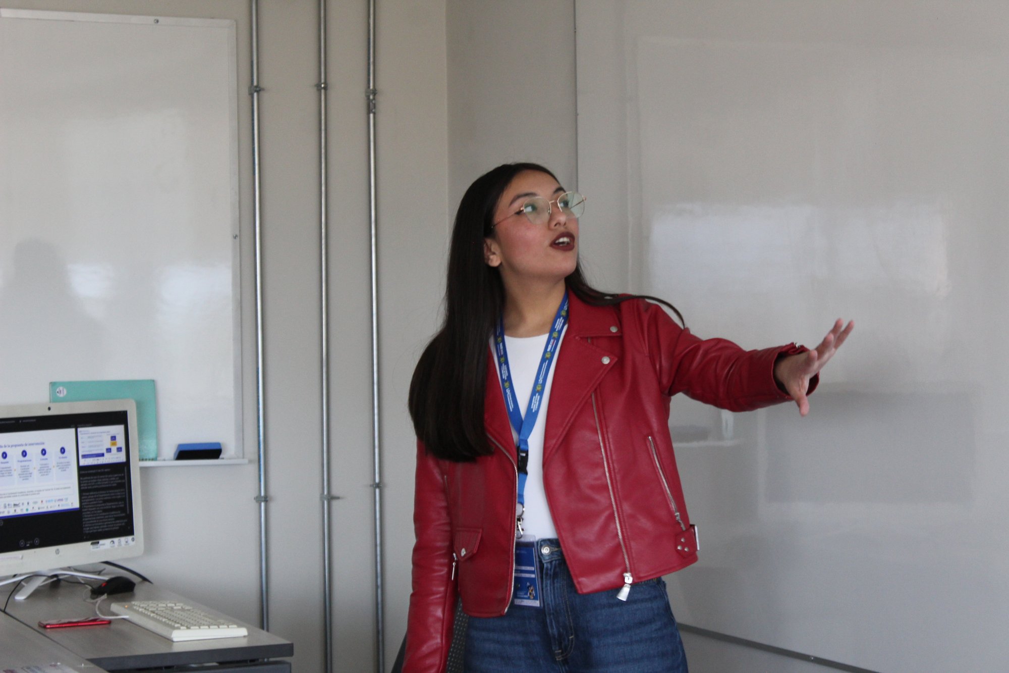 Una participante expone frente a una sala de clases.