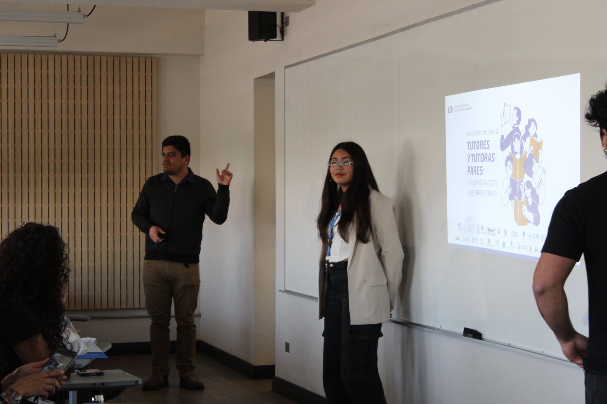 Dos expositores presentan una experiencia en una sala.