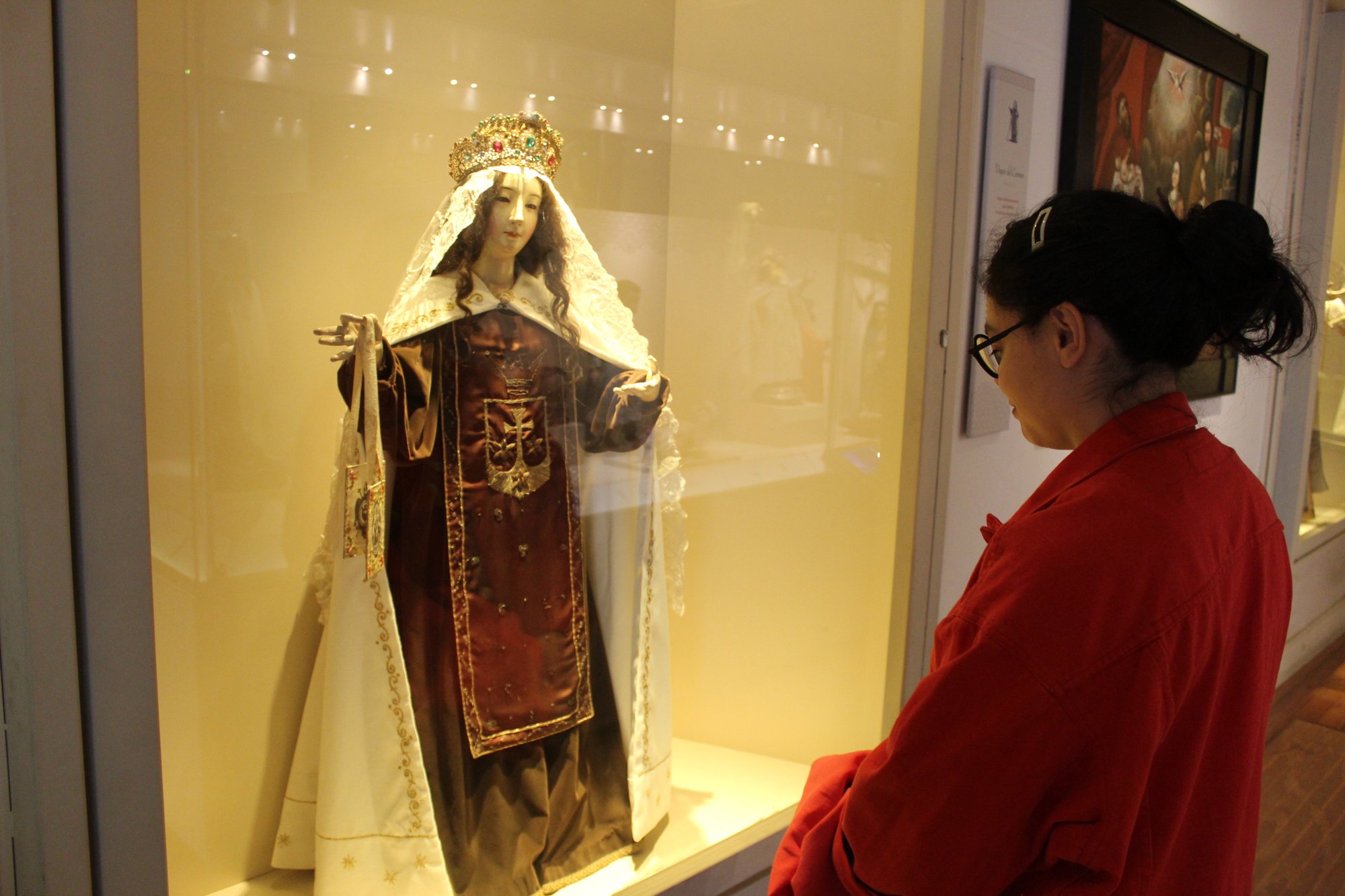 Una persona observa una figura expuesta detrás de una vitrina.