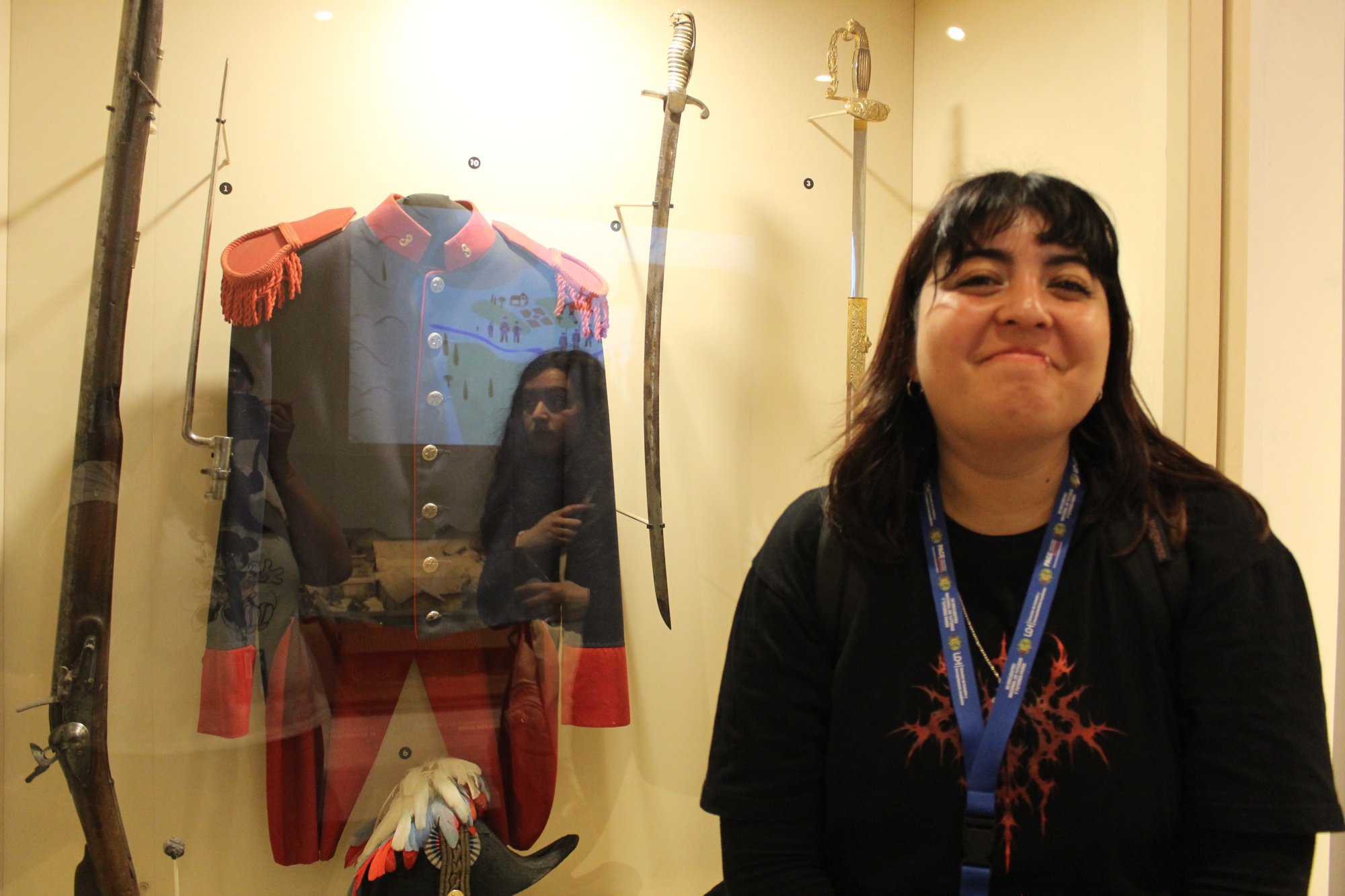 Una persona posa junto a una vitrina que contiene un uniforme.