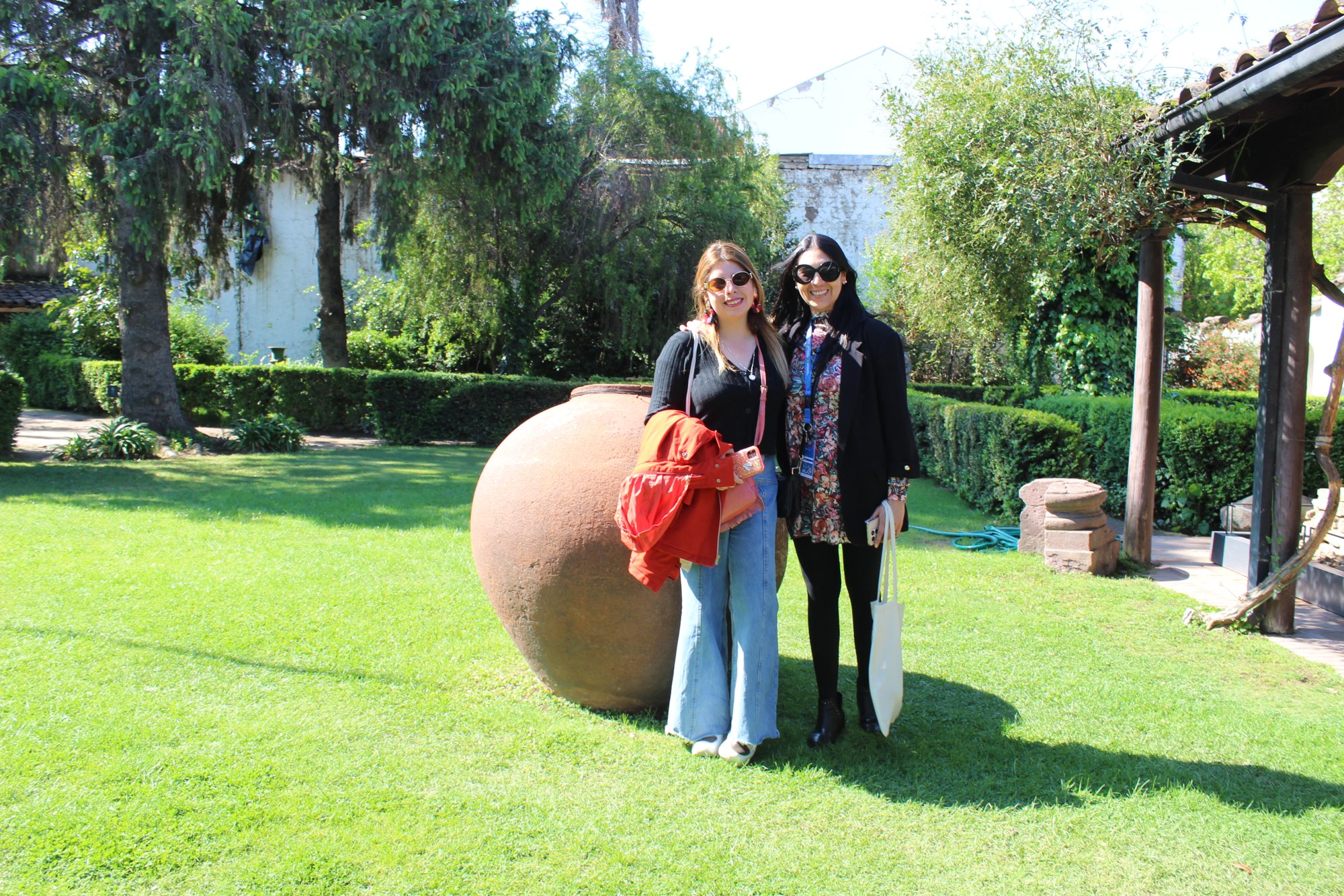Dos personas posan junto a una vasija de gran tamaño en un jardín.