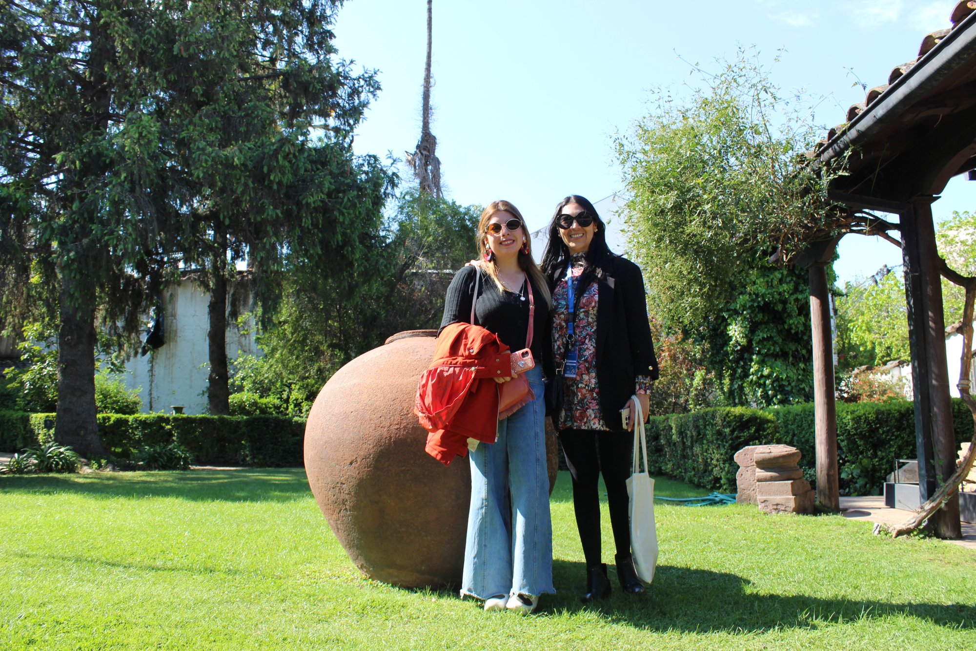 Dos personas permanecen junto a una vasija de gran tamaño en un jardín.