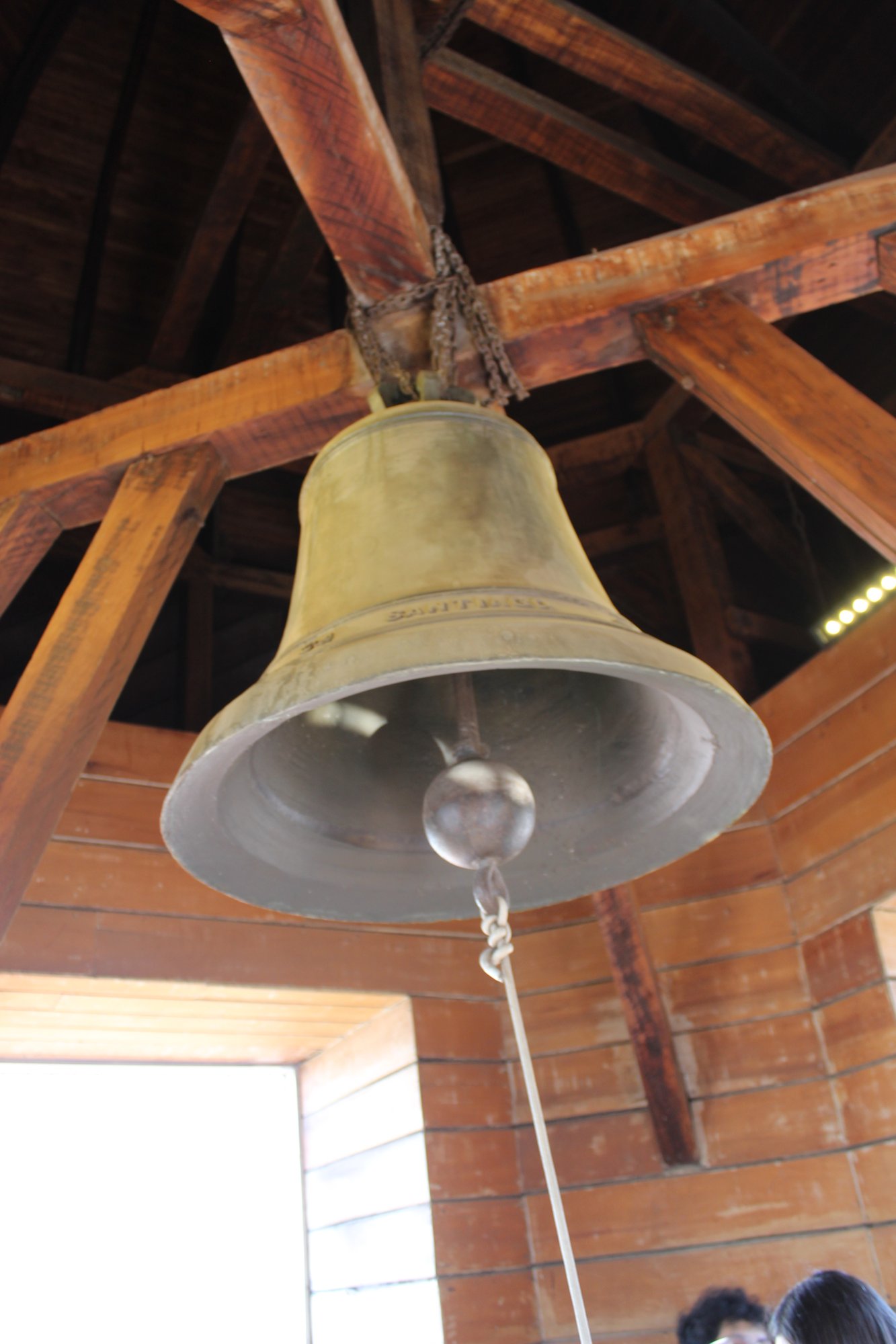 Detalle de una campana suspendida de una estructura de madera.
