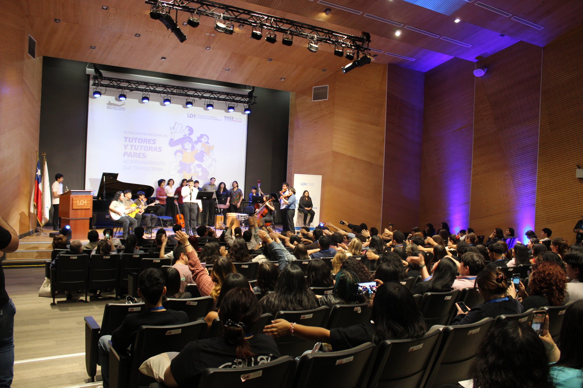 El público levanta las manos frente al conjunto musical en el escenario.
