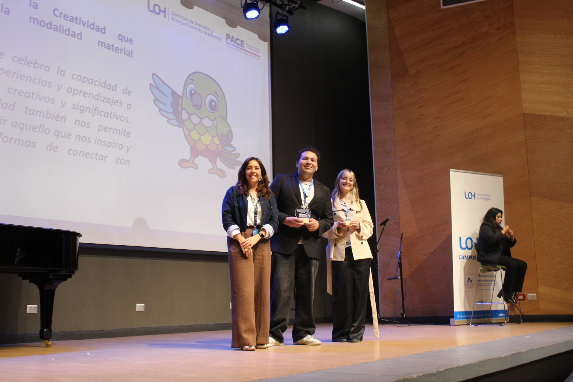 Tres personas posan en una vista amplia del escenario del auditorio.