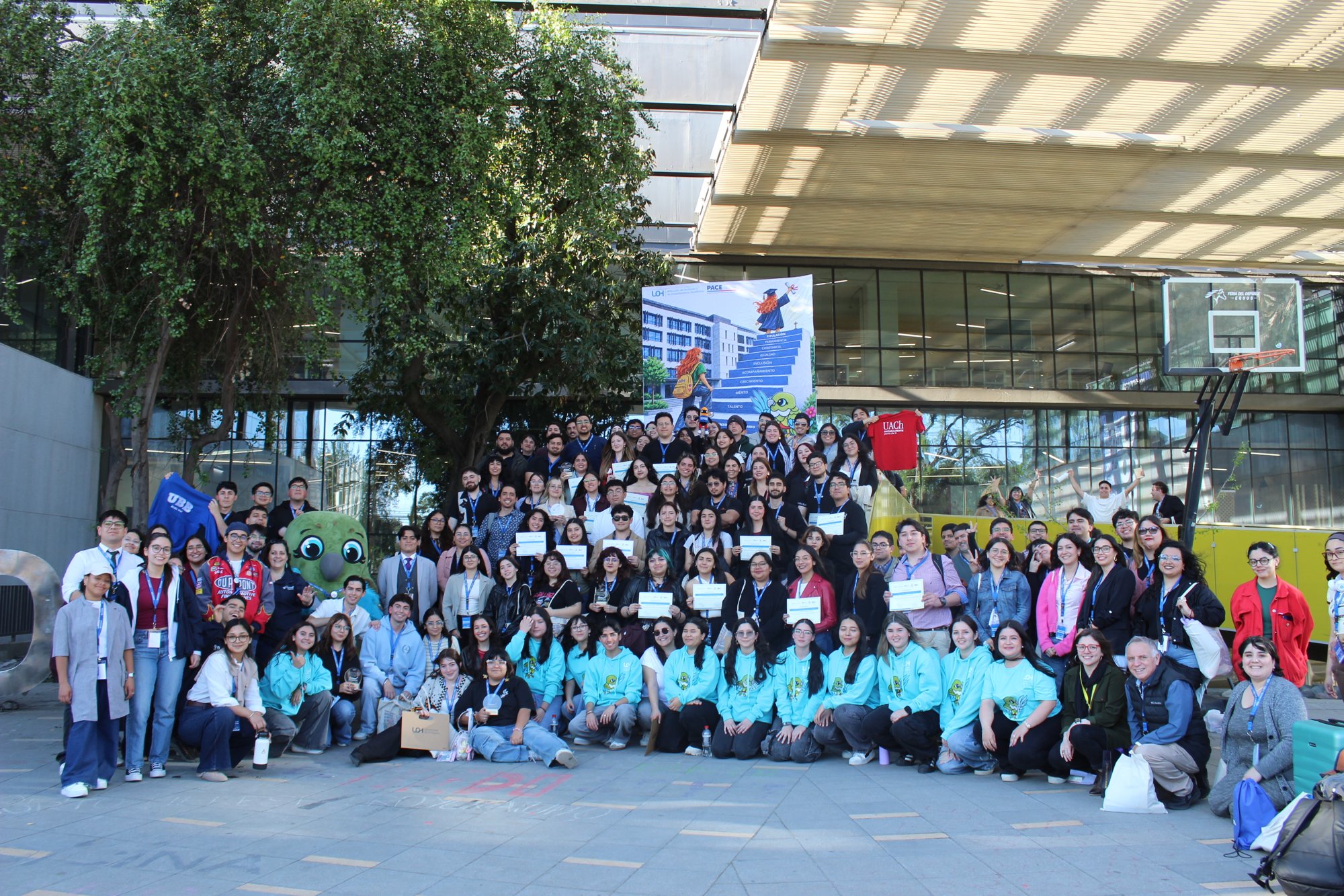 Un grupo numeroso posa al aire libre, con varias personas sosteniendo diplomas.